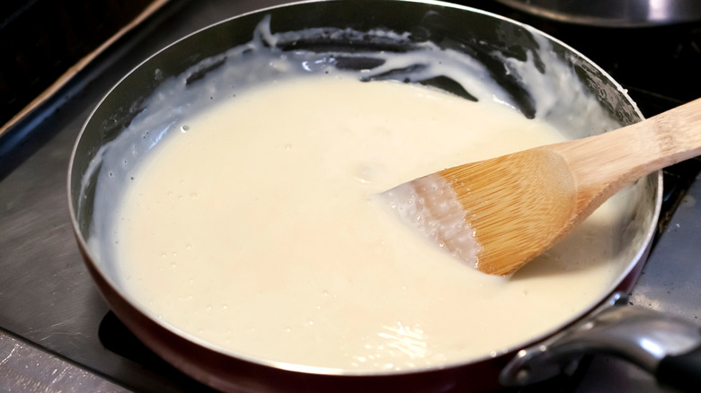wooden spoon with creamy roux in pan