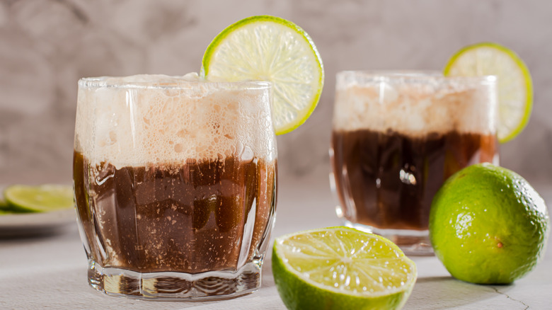 Two glasses of dirty sodas with lime and a lime sliced in half.