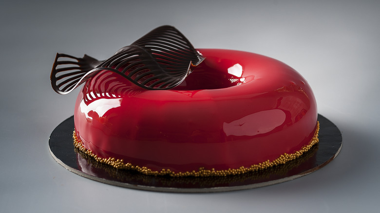 Red mirror glaze ring cake with a decorative chocolate leaf