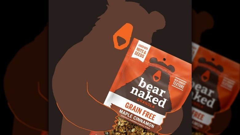 The Bear Naked mascot hugging a back of Maple Cinnamon granola.