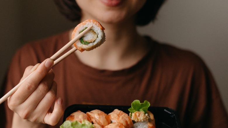 Woman eating sushi with chopsticks