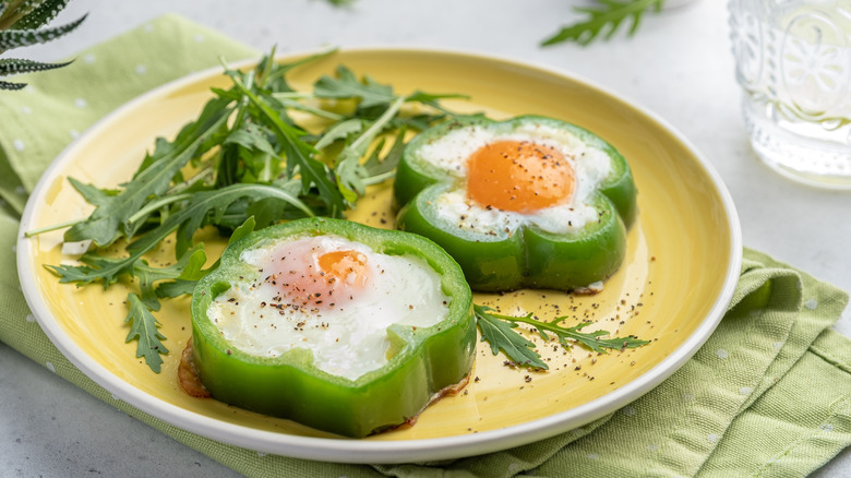 eggs sunny side up in a green bell pepper ring with rocket lettuce