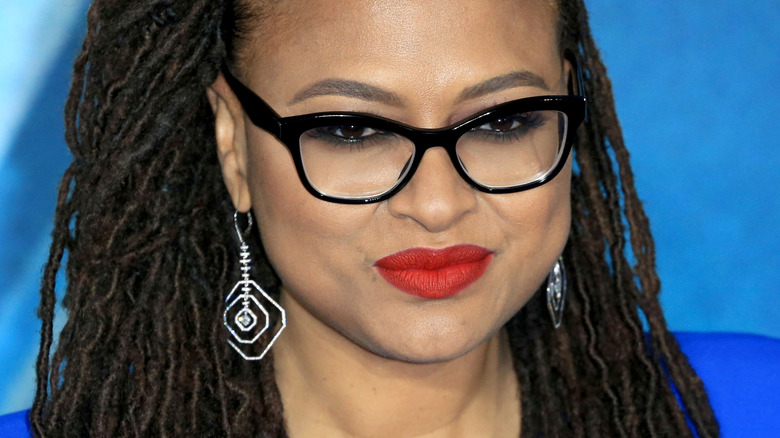 Ava DuVernay with red lipstick, glasses and slight smirk