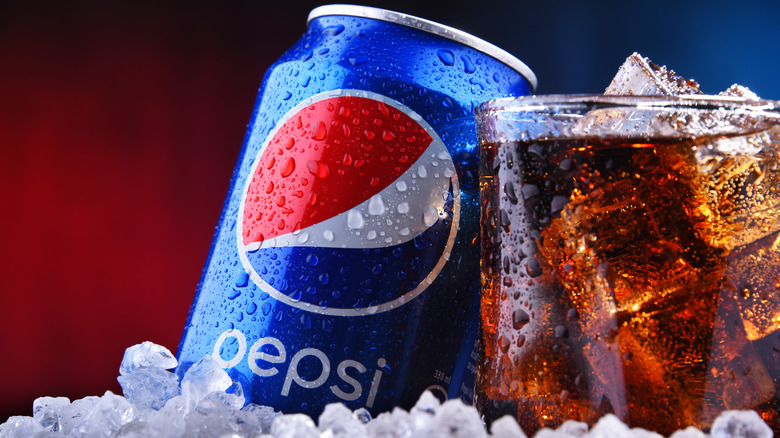Pepsi can and glass filled with soda and ice