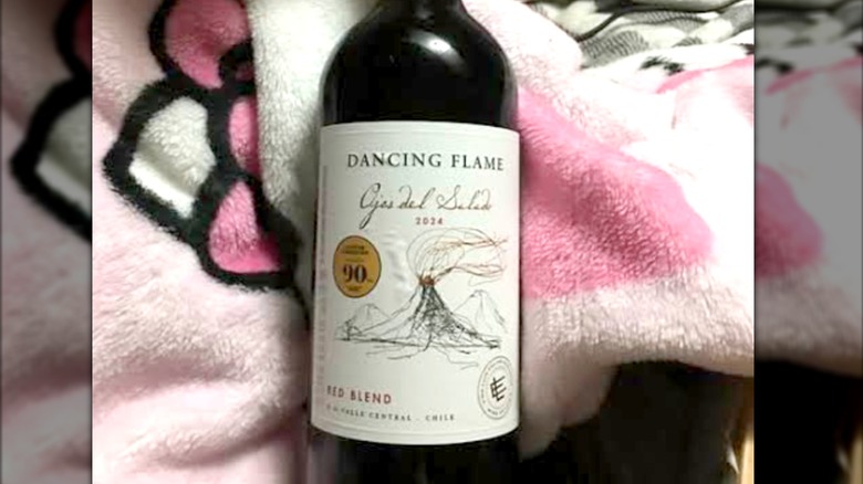 A bottle of red wine laying on a blanket