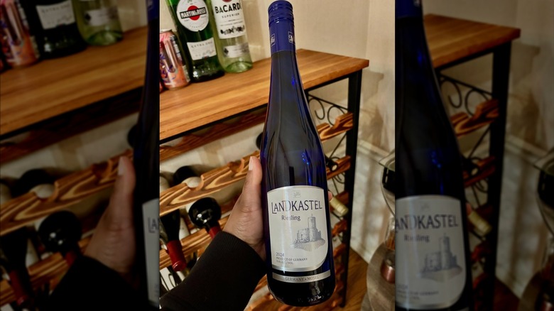 Hand holding bottle of Riesling in front of home bar