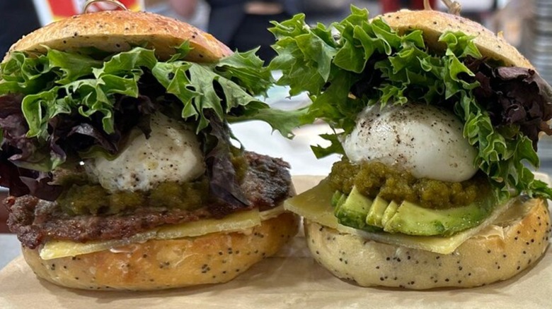 Two sandwiches on buns stuffed with eggs, lettuce, etc.