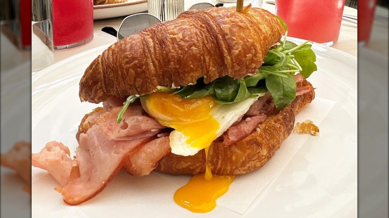 croissant sandwich with ham and dripping egg