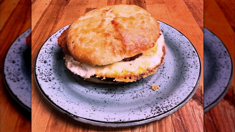 Egg and hashbrown on a biscuit sandwich on blue speckled plate