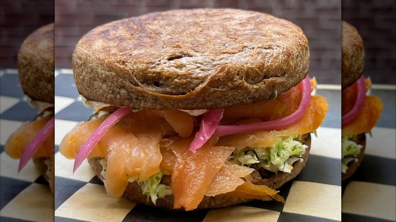 English muffin sandwich with smoked salmon and red onions on checkered paper