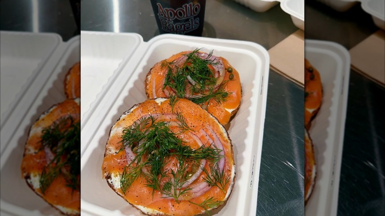 Sliced bagel with smoked salmon, onions, capers, and dill in to-go box