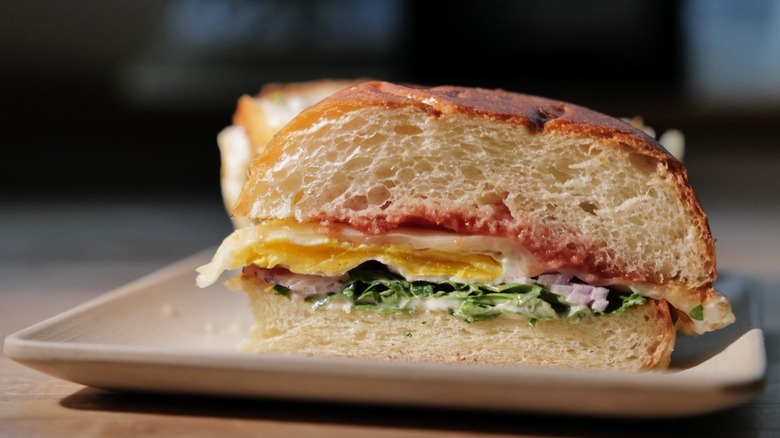 Breakfast sandwich with cheese, eggs, greens, and tomato jam on brioche