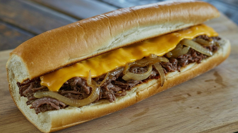 A Philly cheesesteak with onions on a wooden board