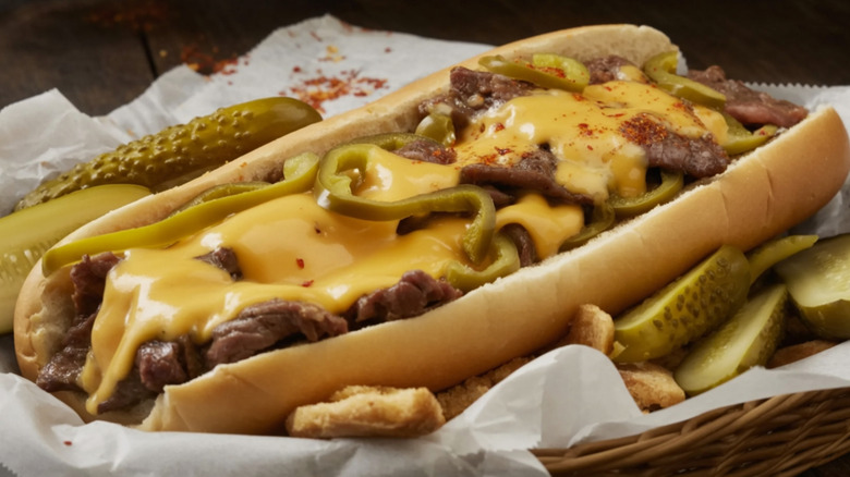 A classic cheesesteak topped with peppers in a basket lined with parchment paper