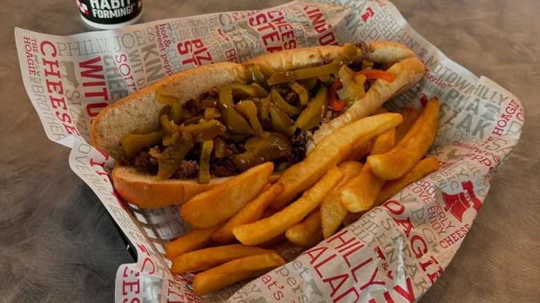 A cheesesteak along with fries from The Cheese Steak Shop in a basket lined with paper