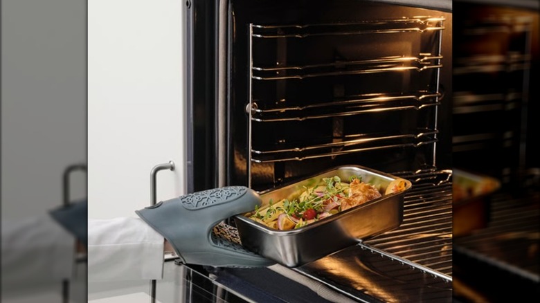 IKEA 365+ stainless steel container being placed in an oven by a covered hand