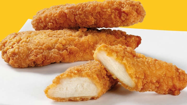 Close-up of chicken tenders, one in foreground is cut in half