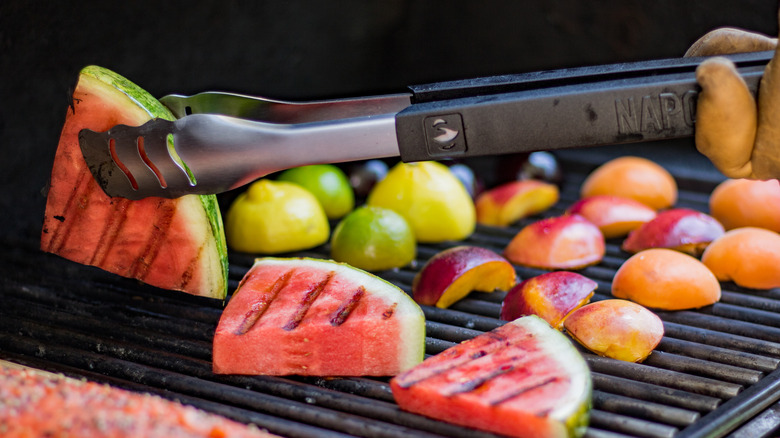 A closeup shot of a barbecue with watermelon, citrus, peaches, and tangerines