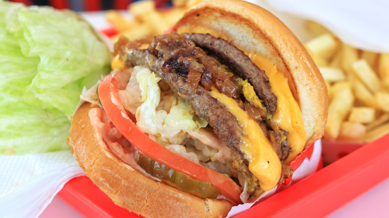 an In-N-Out double-double animal style burger with grilled onions and pickles visible.