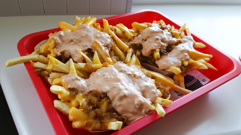 three orders of animal style fries on a red tray.