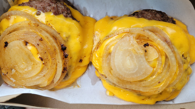 two double cheeseburgers with grilled onions where buns should be.