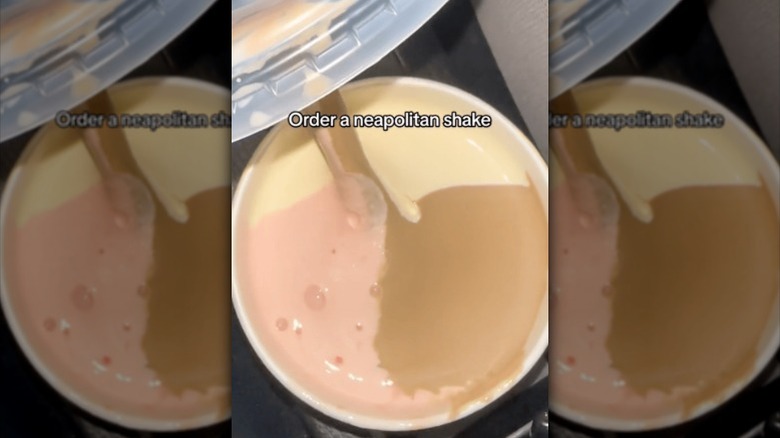 an open cu revealing a strawberry, vanilla, and chocolate shake.