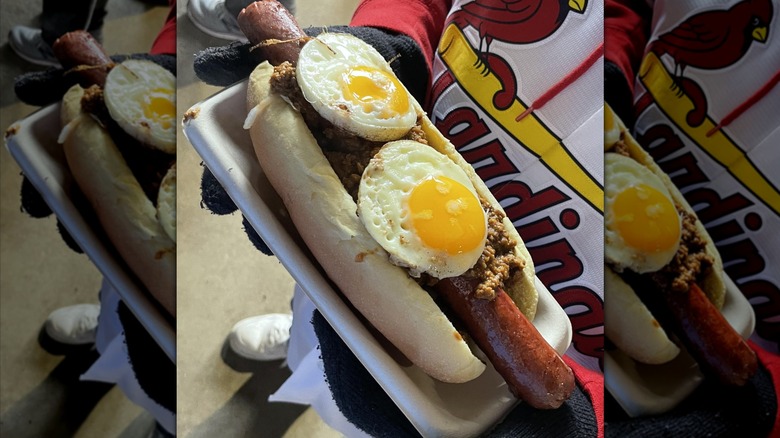 cardinals fan holding a slinger hot dog topped with eggs