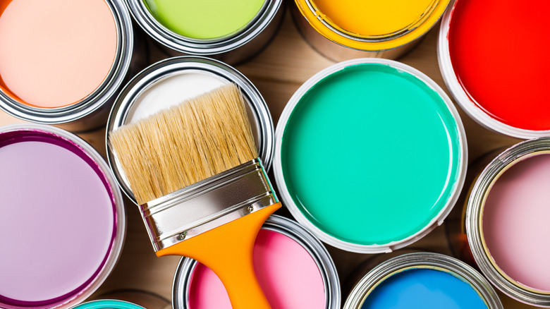 A variety of bright colors of paint in open tins, shot from above