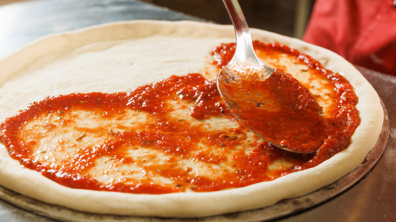 Spreading sauce on pizza