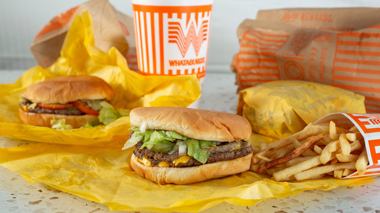 3 burgers from Whataburger (1 still wrapped) with fries and a soda