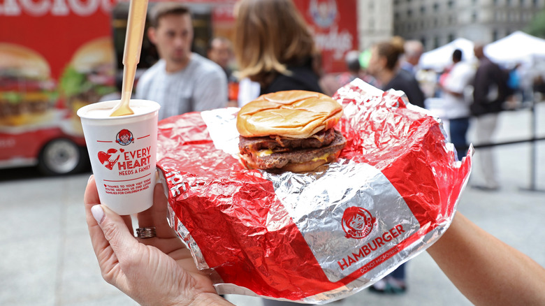Hand holding baconator and junior frosty
