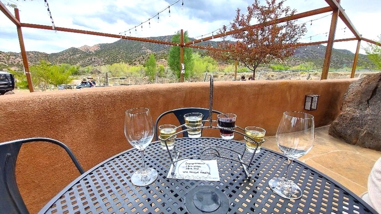 A flight of small wines on a table with empty glasses, in front of desert landscape