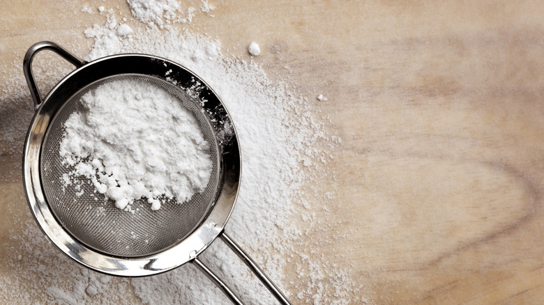 Powdered sugar and a sieve on a wooden table