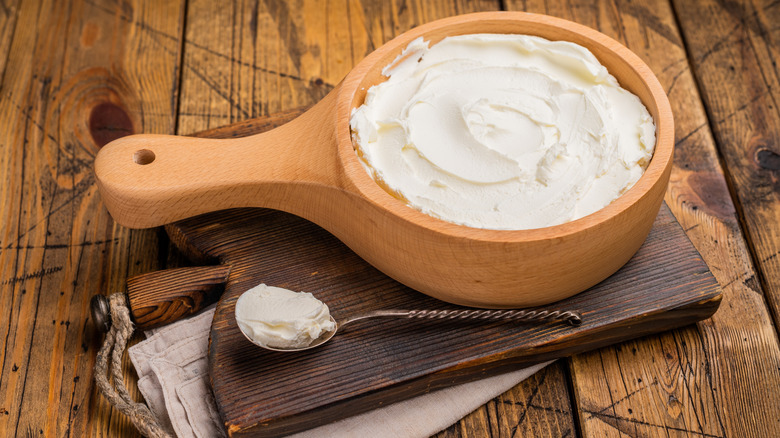 Mascarpone cheese in a wooden bowl with a spoon on the side