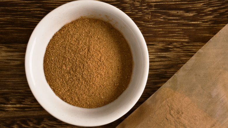 Five spice powder in a white bowl placed on a wooden table