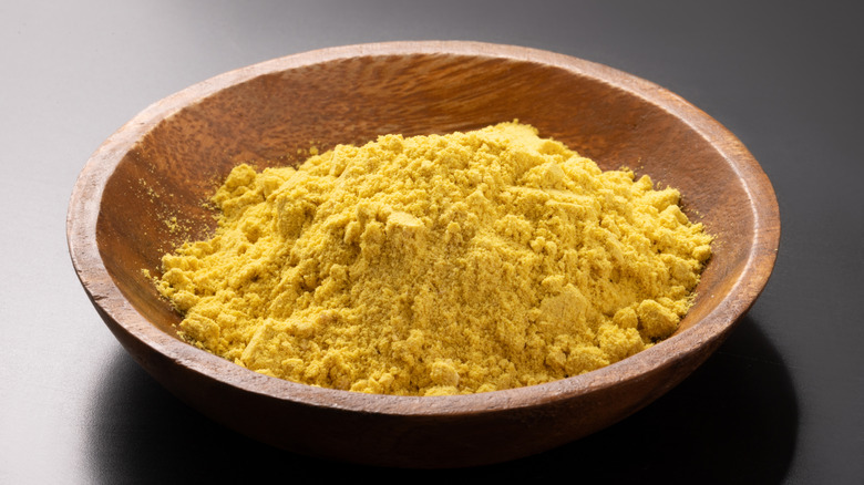 Mustard powder in a wooden bowl placed on a black table