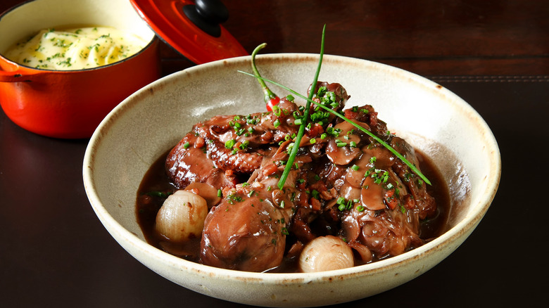 Coq au vin stewed chicken in bowl next to mashed potatoes