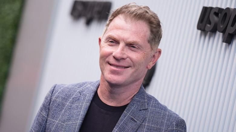 Bobby Flay smiling in a gray jacket and black shirt