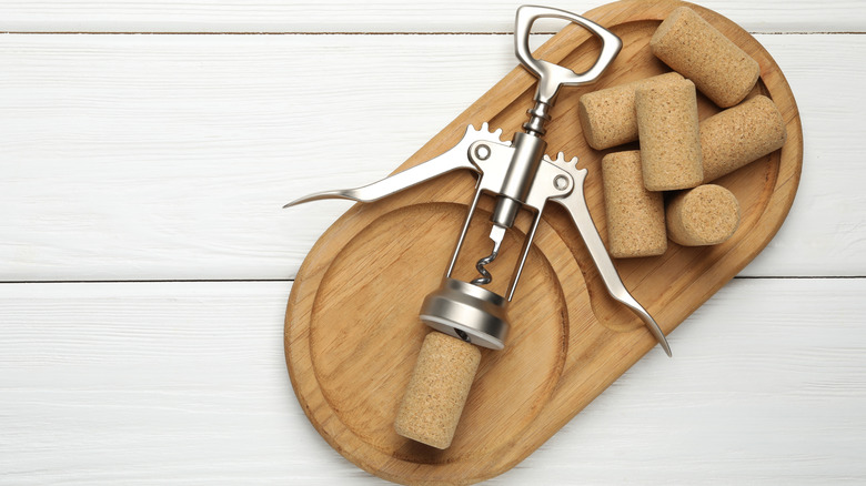 Wing corkscrew on a wooden cheese and wine board with corks