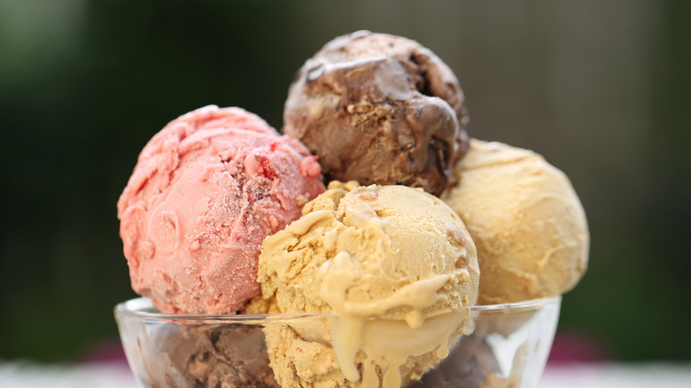 Close-up of chocolate, strawberry, and vanilla scoops of ice cream in a clear glass bowl