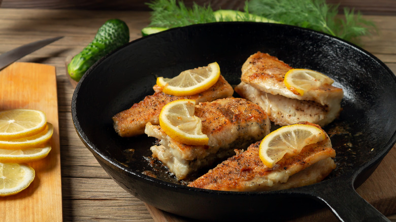 Fish topped with lemon in a cast iron skillet