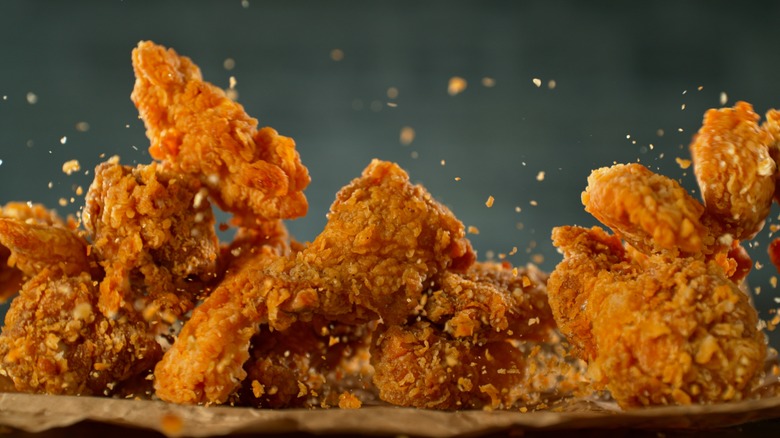 Crispy fried chicken falling onto parchment