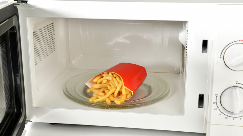 A red container of French fries in a microwave