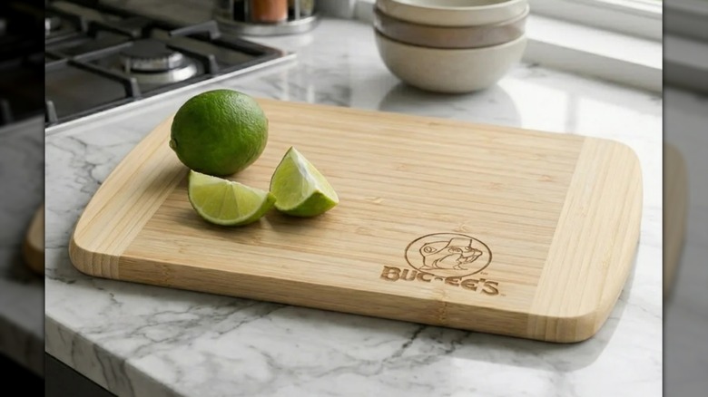 Limes sitting on a Hana cutting board with Buc-ee's logo on a marble countertop