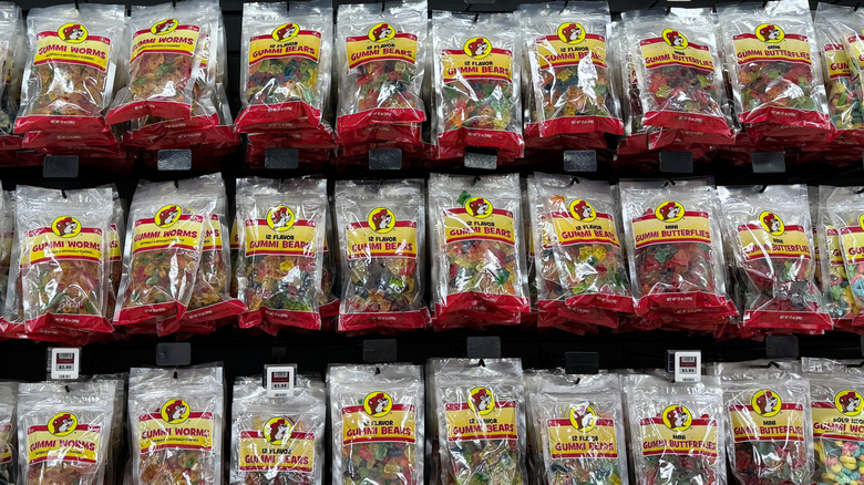 A Buc-ee's display of various gummy candy bags hanging on hooks at the store