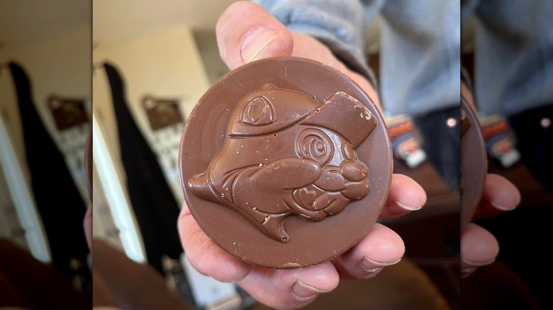 A hand holding large chocolate circle with the Buc-ee's mascot's face printed on it