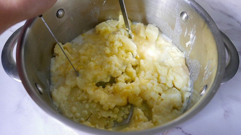 potatoes being mashed in pot