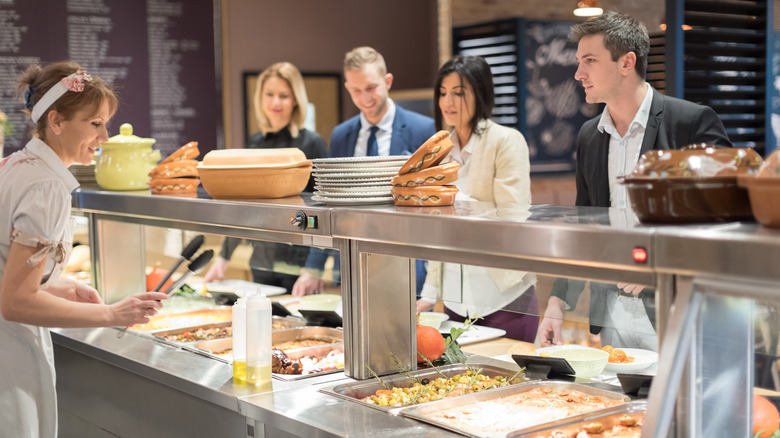 People lined up to get their food at a cafeteria-style restaurant