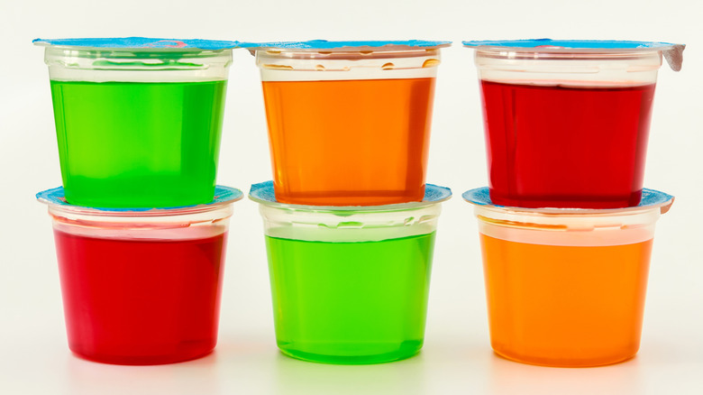 Plastic cups filled with various flavors of Jell-O placed on a white table