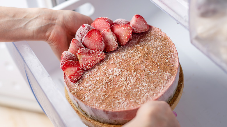 Person putting cake in fridge